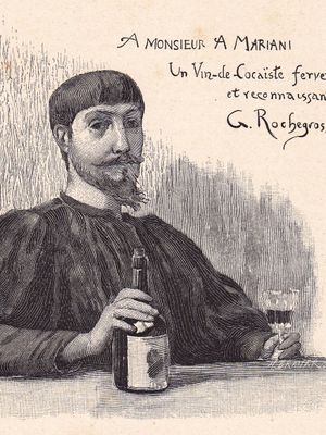Homme barbu et moustachu assis à une table un verre de vin dans une main, la bouteille dans l'autre..