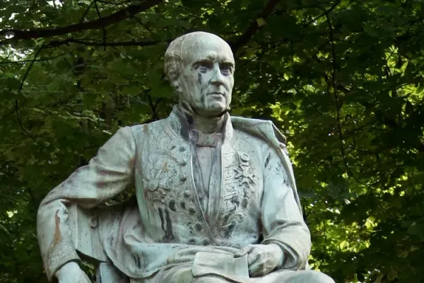 statue d’un homme assis sur une chaise, un bras sur le dossier. Il est habillé d’un vêtement sur lequel sont fixées les décorations qu’il a obtenues.