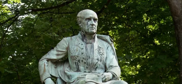 statue d’un homme assis sur une chaise, un bras sur le dossier. Il est habillé d’un vêtement sur lequel sont fixées les décorations qu’il a obtenues.