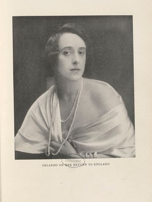 portrait en buste d’une femme aux cheveux bouclés et courts. Elle porte un collier de perles et un vêtement décolleté qui laisse apparaître son épaule gauche. Elle regarde l’objectif.