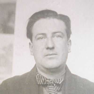 Portrait photographique en noir et blanc d'un homme en veste sombre et nœud papillon rayé.