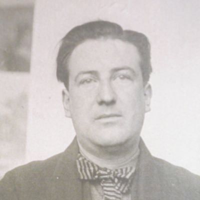 Portrait photographique en noir et blanc d'un homme en veste sombre et nœud papillon rayé.