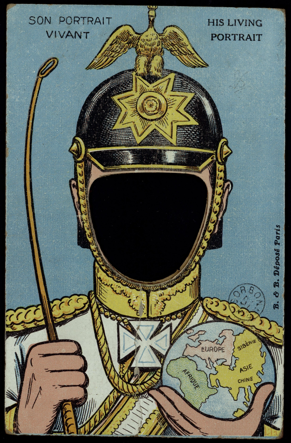 Carte à système à trou (Son Portrait Vivant / His Living Portrait) : buste d'un officier en grand uniforme tenant un globe et une badine, casque à aigle impérial, visage remplacé par un ovale découpé dans lequel le destinataire glisse sa photographie.