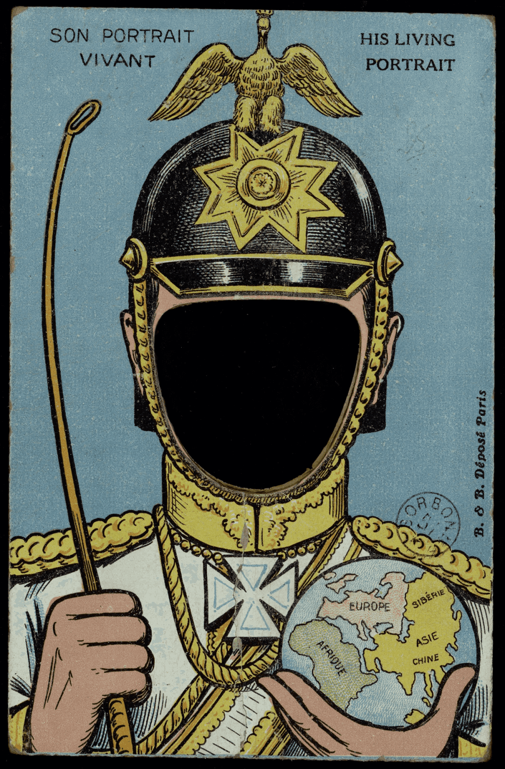 Carte à système à trou (Son Portrait Vivant / His Living Portrait) : buste d'un officier en grand uniforme tenant un globe et une badine, casque à aigle impérial, visage remplacé par un ovale découpé dans lequel le destinataire glisse sa photographie.