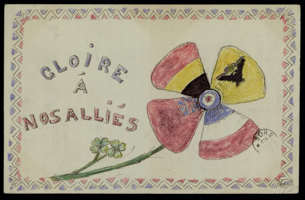 Carte dessinée au crayon par un enfant : une fleur dont les quatre pétales portent les couleurs des drapeaux des pays alliés (France, Belgique, Royaume-Uni, empire russe), cocarde tricolore française au centre, bordure tricolore.