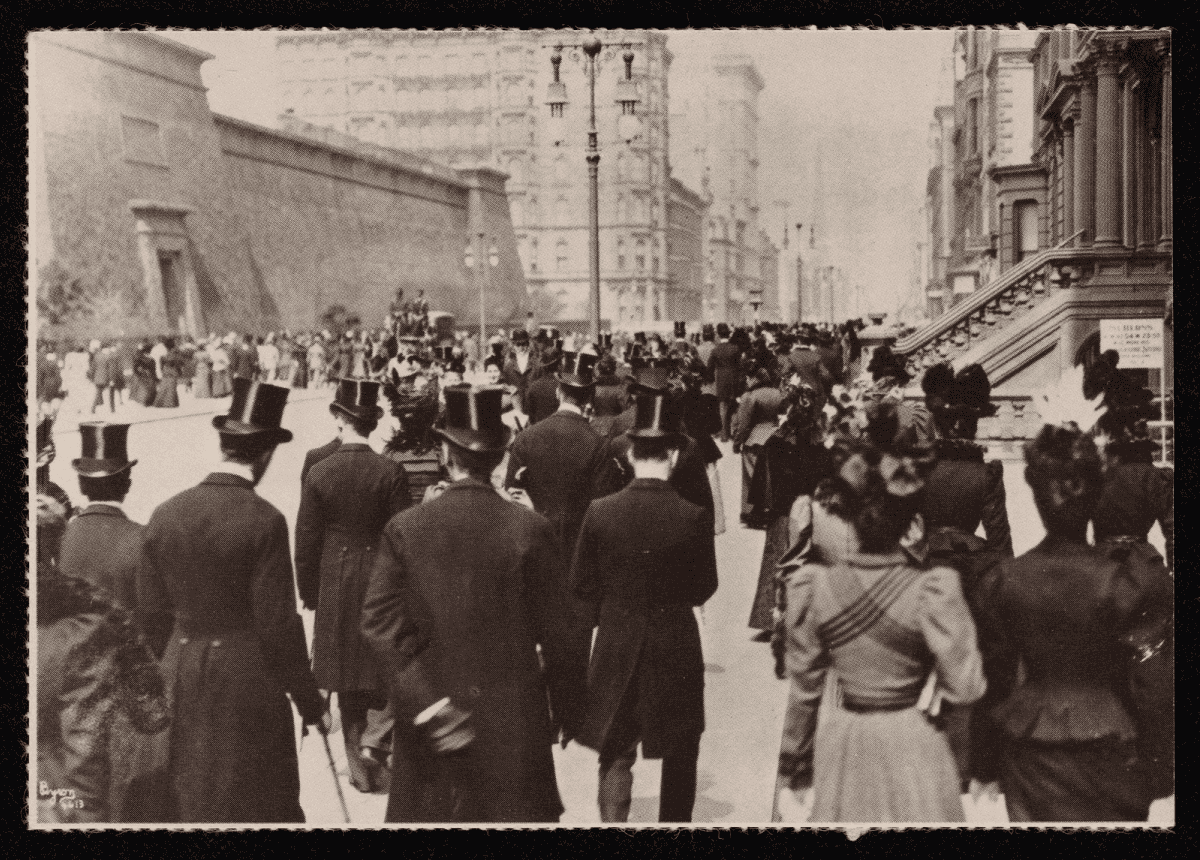 Carte postale montrant une rue urbaine du début du XXe siècle, avec hommes en hauts-de-forme et femmes en robes longues vus de dos.