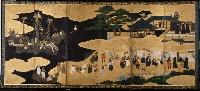 Paravent en six panneaux à fond doré et nuages noirs : un navire portugais à gauche, cortège de marchands et missionnaires au centre portant des vêtements occidentaux et des parasols, bâtiments japonais à droite.