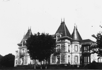 Photographie en noir et blanc d'un château vu de trois quarts, arbres devant la façade.